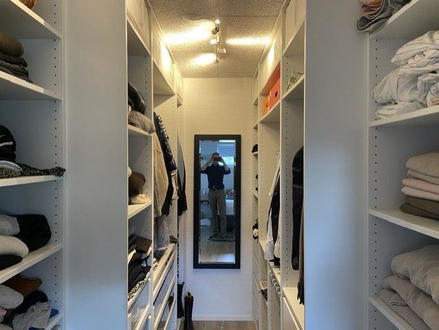 Mobilfoto af et walk-in-closet med fotografen synlig i spejlet